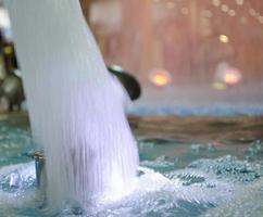 verschwommen Wasser Hintergrund. von hinten beleuchtet Wasser Jet im das Brunnen. foto