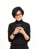 halten und mit Smartphone mit lächelnd Gesicht von gut aussehend asiatisch Mann isoliert auf Weiß Hintergrund foto