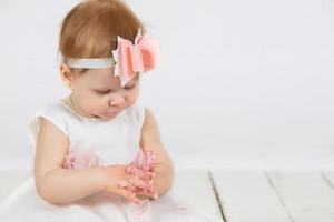 das wenig Mädchen verschmiert ihr Hände mit Creme. foto