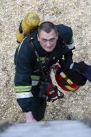 Feuerwehrmann. ein Mann im ein Feuerwehrmann passen sieht aus hoch. brutal Feuerwehrmann. Löschen ein Feuer. foto