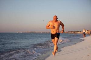 ein Alten Mann joggt entlang das Küste. foto