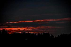 bunt Sonnenuntergang mit rot Himmel und Bäume und Wolken foto