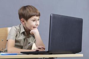 primär Schule Schüler beim das Tabelle mit ein Laptop. foto