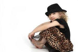 schön Kind. wenig blond Mädchen im ein schwarz Hut auf ein Weiß Hintergrund. ein vier Jahr alt Kind ist Sitzung. Modell- Kind. foto