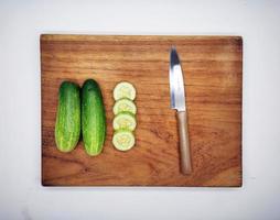 Gurken auf ein hölzern Schneiden Tafel und Küche Messer. foto