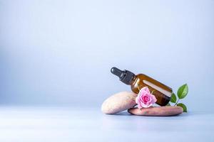 Glas Flasche mit Pipette zum ein kosmetisch Produkt mit ein Rose auf Steine foto