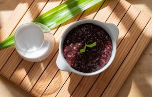 schwarz klebrig Reis Haferbrei mit Kokosnuss Milch Soße serviert im ein Weiß Schüssel. indonesisch traditionell Dessert foto