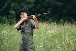 Frau auf Natur Jagd mit ein Gewehr im Grün Overall Grün Blätter foto