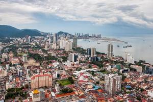 Antenne Aussicht von das Stadt von Georgetown und das Küste mit Schiffe auf das Insel von Penang im Malaysia. das Wetter ist wolkig. viele von hoch Gebäude und klein Häuser. foto