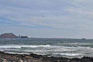 Meer Landschaft mit das Ozean und ein Aussicht von das Spanisch Insel von de Lobos mit ein Schiff im das Hintergrund foto