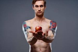 sportlich Männer Bodybuilding Fitness Drücken Sie gepumpt oben Arm Muskeln tätowieren rot Apfel foto