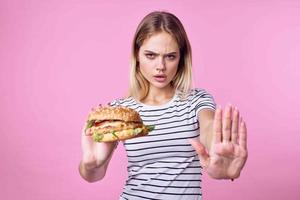 süß blond Mädchen im gestreift T-Shirt Hamburger Nahansicht schnell Essen Lebensstil foto