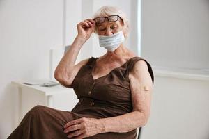Alten Frau tragen Brille mit ein Pflaster auf ihr Arm Impfstoff Reisepass Krankenhaus foto
