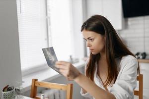 Frau tun Gesicht bilden und Spiegel im Hand Fenster im das Hintergrund foto