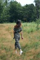 Frau Spaziergänge auf Natur im ein Feld von Grün Bäume foto