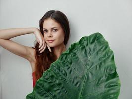 Frau halten Hand in der Nähe von Gesicht Palme Blatt Charme Licht Hintergrund foto