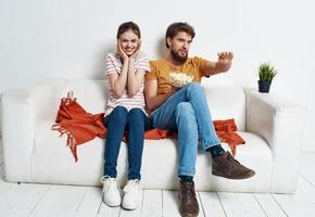 ein Mann und ein Frau auf das Couch Aufpassen Fernseher im ein hell Zimmer foto