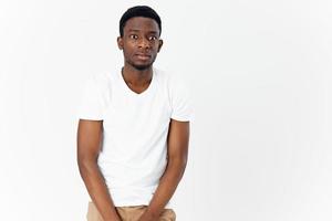 gut aussehend Mann von afrikanisch Aussehen mit überrascht Augen im ein Weiß T-Shirt Licht Hintergrund foto
