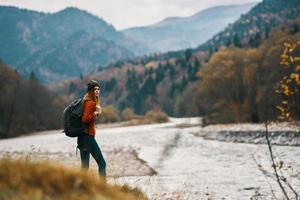 Frau mit Rucksack Wandern durch das Fluss im das Berge Landschaft foto