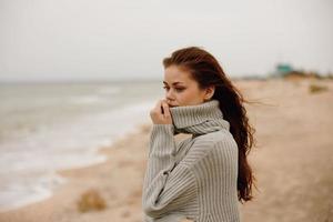 heiter Frau im ein Sweatshirt fliegend Haar durch das Ozean Tourismus Lebensstil foto
