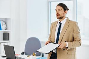 Mann im Beige Jacke im das Büro mit Unterlagen Lebensstil foto