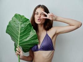 Frau mit Grün Blatt im Hände Badeanzug Charme exotisch Emotionen foto