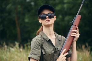 Militär- Frau Schrotflinte Jagd Sonnenbrille Grün Blätter foto