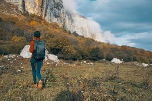 Reisender mit Rucksack sich ausruhen im das Berge draußen im Herbst Landschaft Blau Himmel Felsen foto