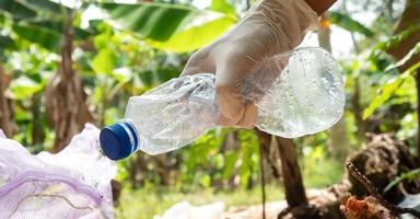 Menschen pflücken oben Plastik Flaschen in Müll Taschen. Landwirtschaft und Klima ändern, Mikroplastik Abfall. Essen und Plastik Verpackung Industrie foto