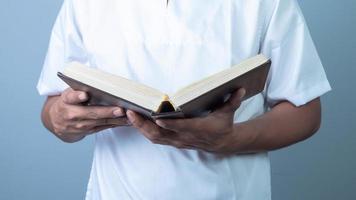 Muslim Mann lesen heilig Buch Koran, isoliert auf Blau Hintergrund foto