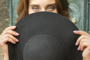 Frau versteckt Gesicht mit Hut foto