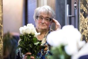 Puan alt Frau mit Rosen sieht aus im das Spiegel. foto