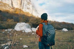 Frau Tourist im ein Hut mit ein Rucksack klettert das Berge im Natur zurück Aussicht foto