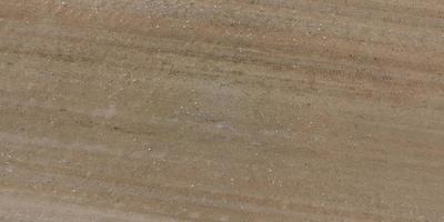 Draufsicht auf die Oberfläche der Schotterstraße aus kleinen Steinen und Sand mit Spuren von Autoreifen foto