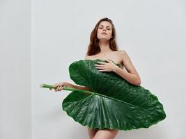 ziemlich Frau mit nackt Körper bedeckt mit Palme Blatt exotisch Luxus foto