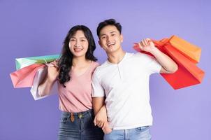 Bild von asiatisch Paar halten Einkaufen Taschen auf lila Hintergrund foto