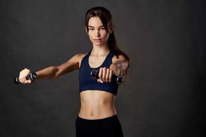 sportlich Frau mit Hanteln im Hände schlank Zahl trainieren Motivation gepumpt oben Muskeln foto
