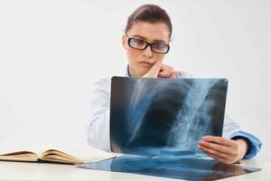 Arzt mit Röntgen sitzt beim das Tabelle Diagnose Behandlung foto