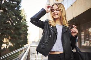 Frau im schwarz Jacke und Straße Natur Herbst Gebäude Einkaufen Modell- foto