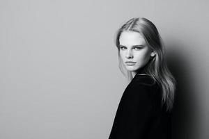 jung ausdrucksvoll schön blond Fachmann Modell- posieren isoliert im Studio Dressing im schwarz Jacke sieht aus beim Kamera. Mode minimalistisch Konzept foto