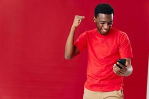 froh Mann mit ein Telefon im seine Hände rot T-Shirt Gesten mit seine Hand Studio foto