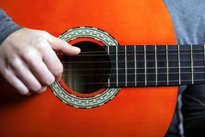 Mann spielt mit akustischer orange Gitarre foto