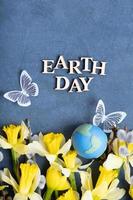 Erde Tag Text mit Globus, Blumen und Schmetterling. glücklich Erde Tag Konzept eben legen, oben Aussicht foto
