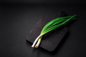 frisch Grün Zwiebeln auf ein hölzern rechteckig Schneiden Tafel foto