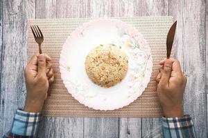 Mann mit Gabel und Messer, der gebratenen Reis isst