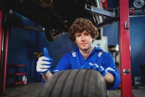 Porträt ein Instandhaltung Techniker inspizieren Reifen im das Garage und Veränderung Legierung Reifen im das Garage. Auto Wartung. Auto Reparatur und Instandhaltung Konzept foto