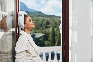 Porträt Frau Stehen auf das Balkon suchen beim das Berge Ferien im das Berge im Sommer- unverändert foto