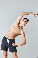 Athlet mit aufgeblasen Arm Muskeln gebogen Über zu das Seite auf ein grau Hintergrund Übung trainieren foto