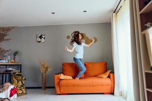 ziemlich Frau im Jeans ist Stehen auf das Couch Spaß foto