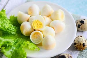 gekocht Eier Essen, Wachtel Eier auf Weiß Platte, Frühstück Eier mit frisch Wachtel Eier und Gemüse Grüner Salat auf Tabelle Hintergrund foto